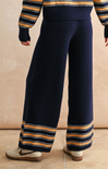Navy blue pants with yellow and black stripes worn by a person on a beige background