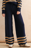 Navy blue pants with yellow stripes worn by a person against a beige background