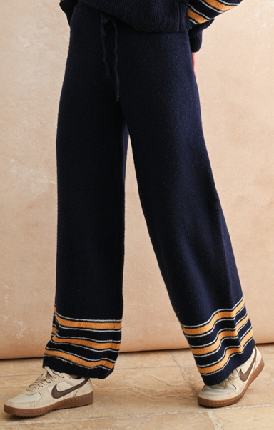 Navy blue pants with striped cuffs worn by a person on a beige background