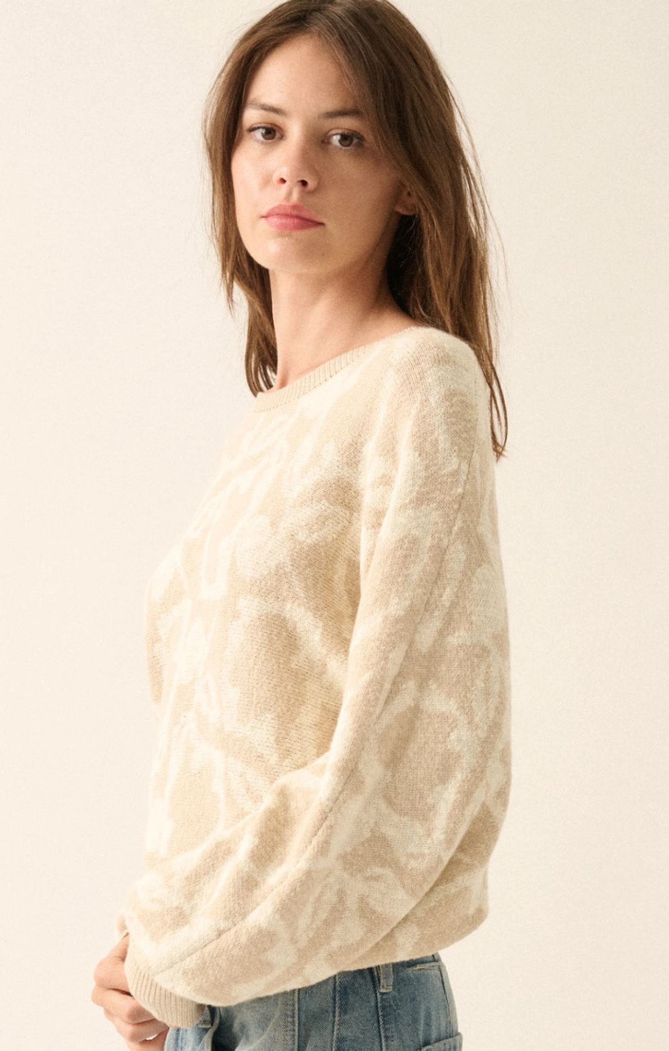 Woman wearing a cream sweater against a plain background