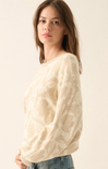 Woman wearing a cream sweater against a plain background