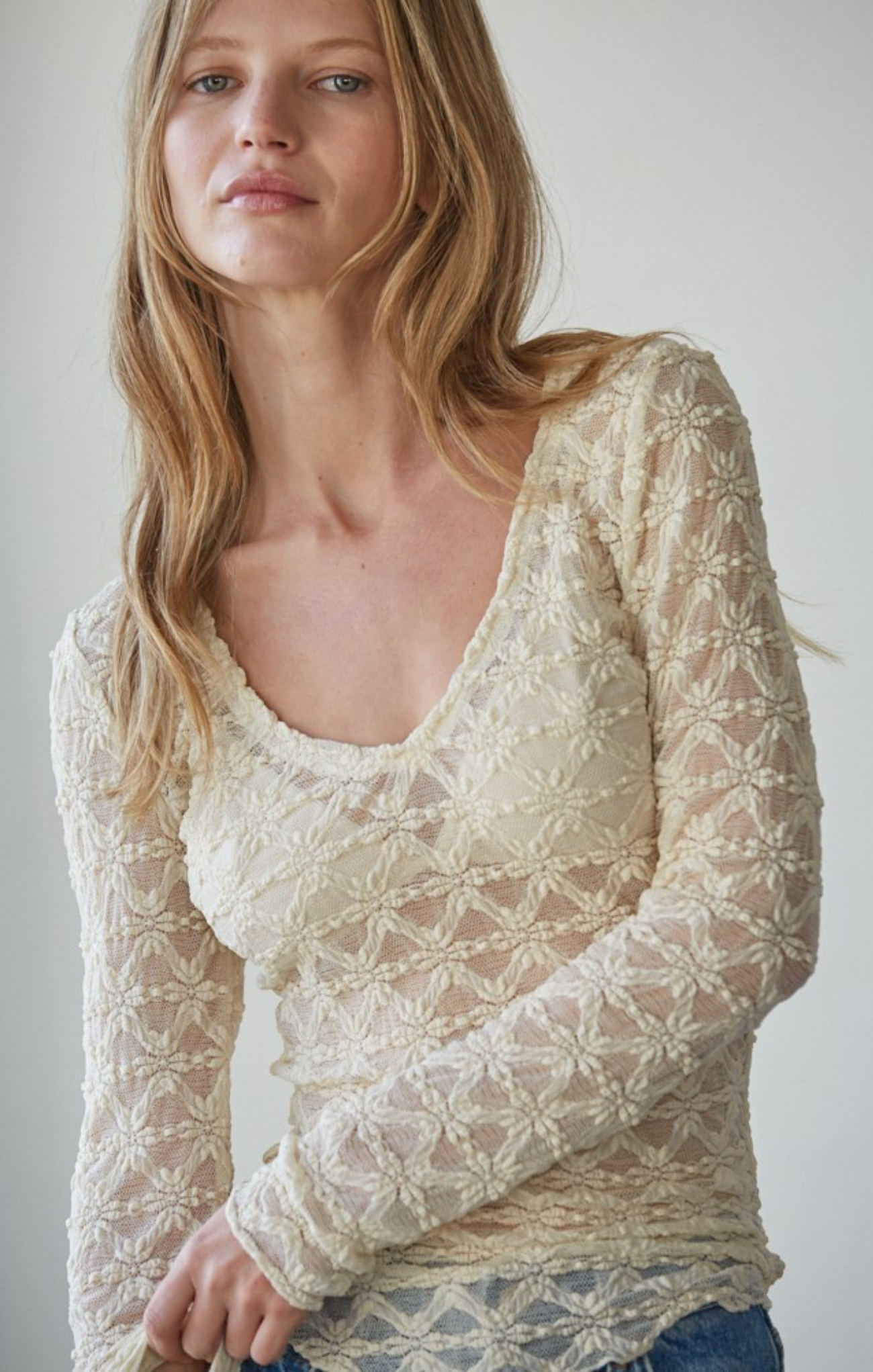 Woman wearing a lace top against a plain background