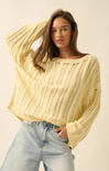 Woman wearing a light yellow sweater and light blue jeans against a plain background