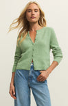 Woman wearing a green cardigan and blue jeans against a plain background