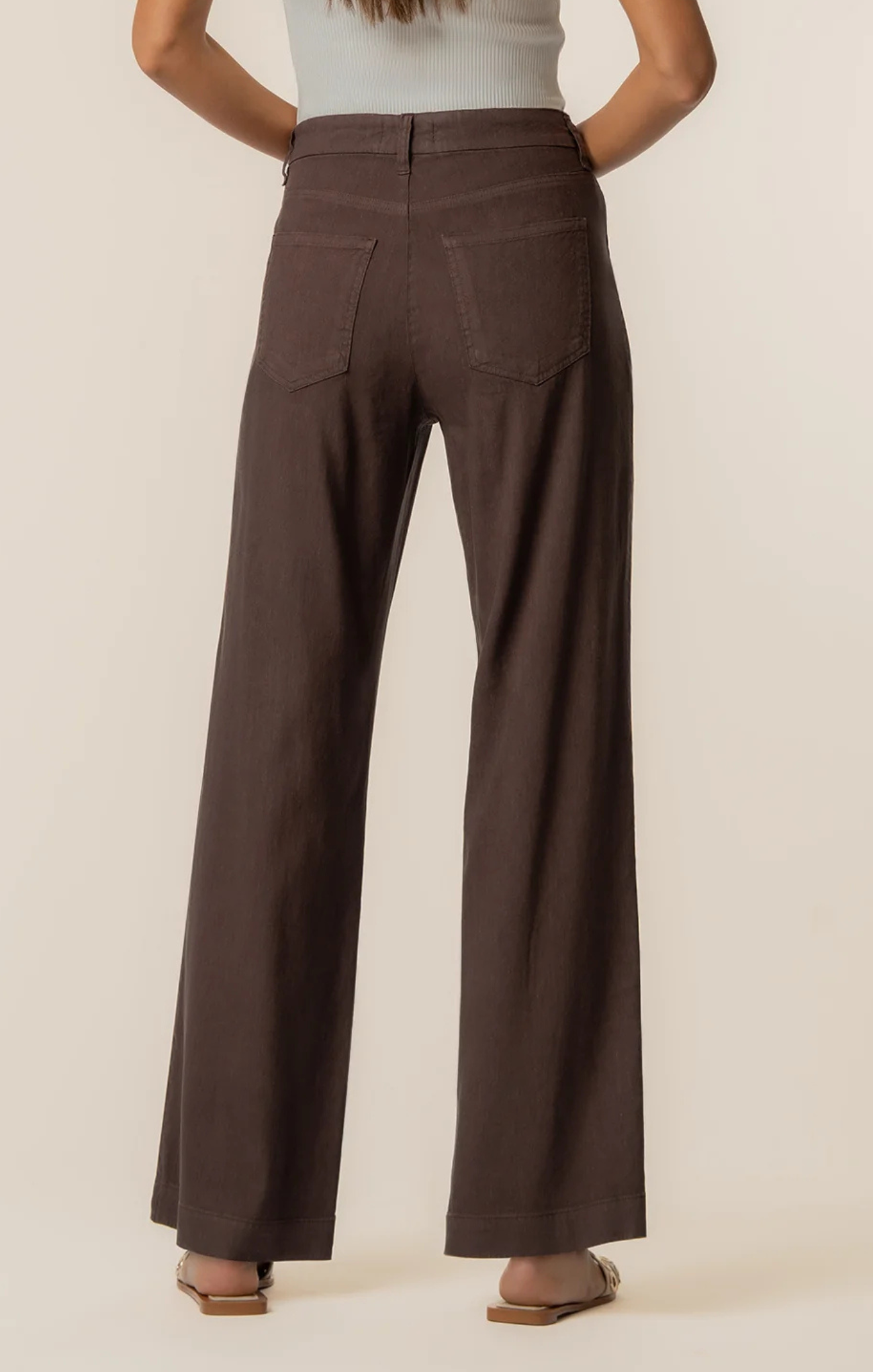 Brown wide-leg pants worn by a person on a beige background