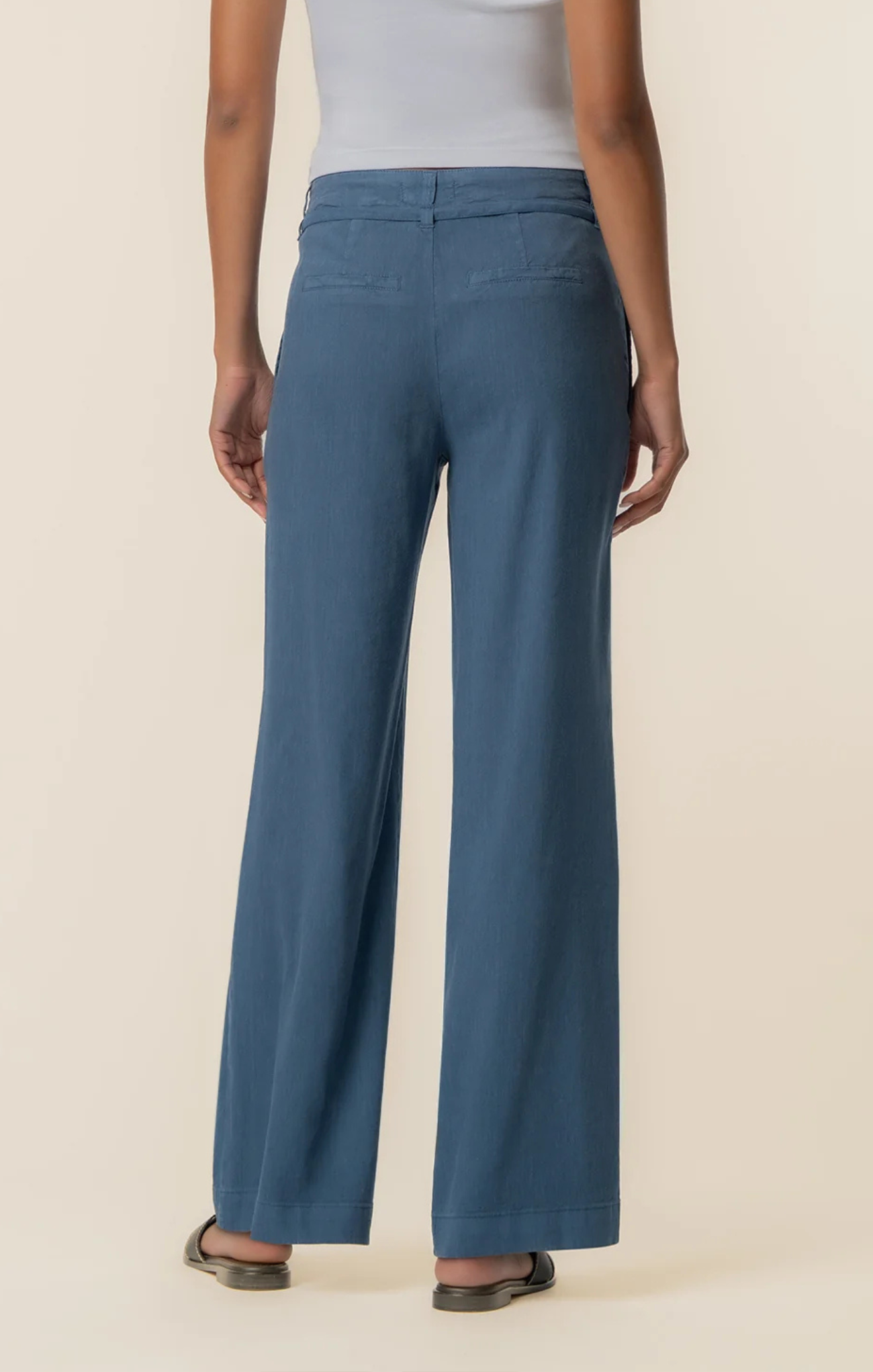 Person wearing blue pants on a beige background