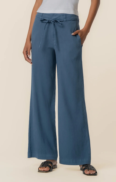 Person wearing blue wide-leg pants on a beige background