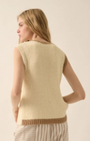 Woman wearing a beige knitted vest against a plain background