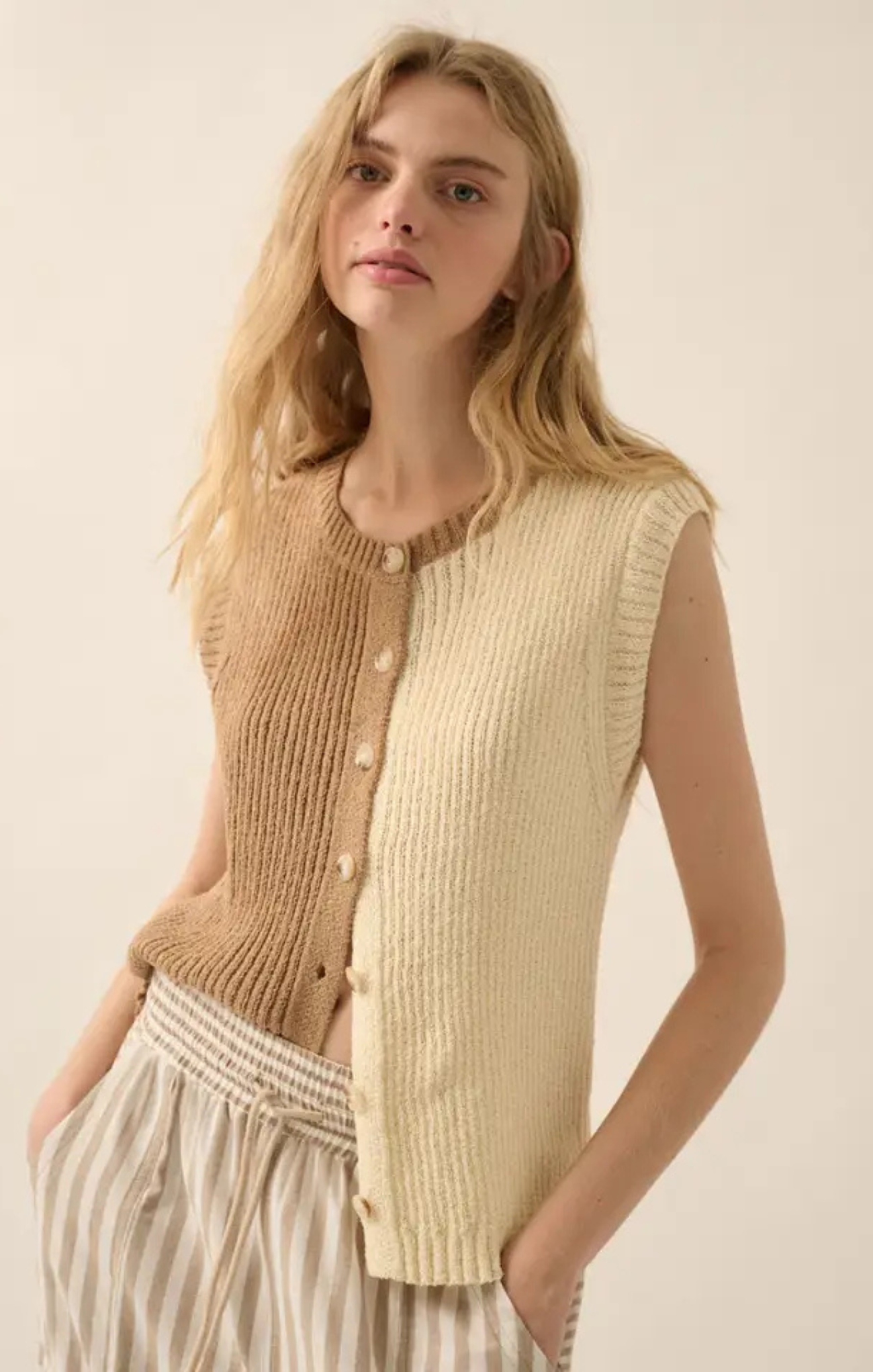 Woman wearing a two-tone knit vest against a plain background