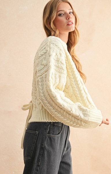 Woman wearing a cream-colored knitted cardigan against a beige background