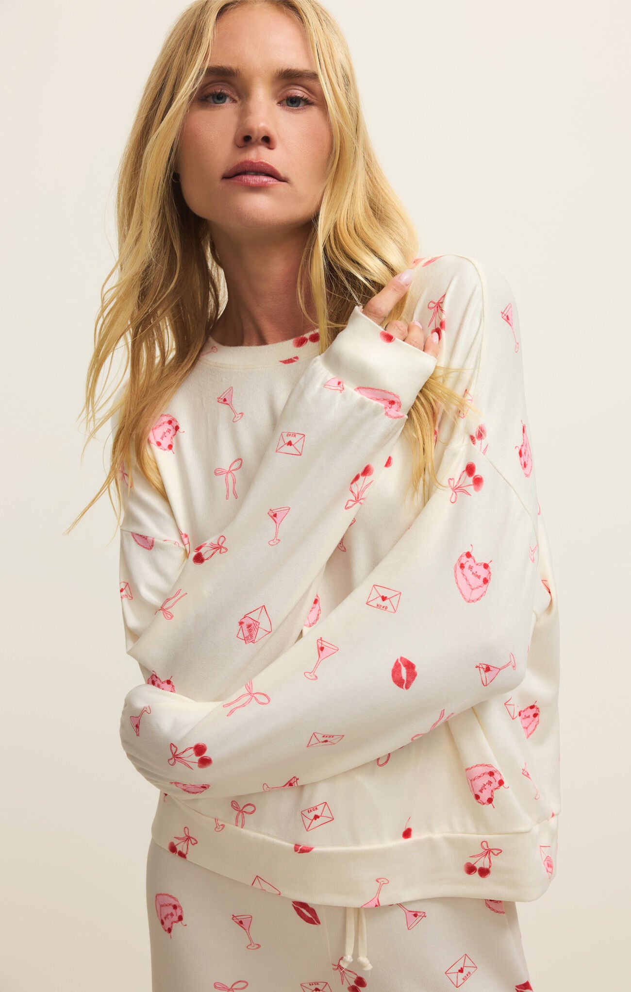 Woman wearing a white sweatshirt with red patterns on a beige background