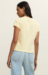 Woman wearing a yellow top and light blue jeans on a beige background