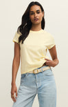 Woman wearing a yellow t-shirt and light blue jeans against a plain background