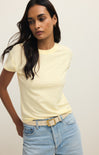Woman wearing a light yellow t-shirt and light blue jeans against a plain background