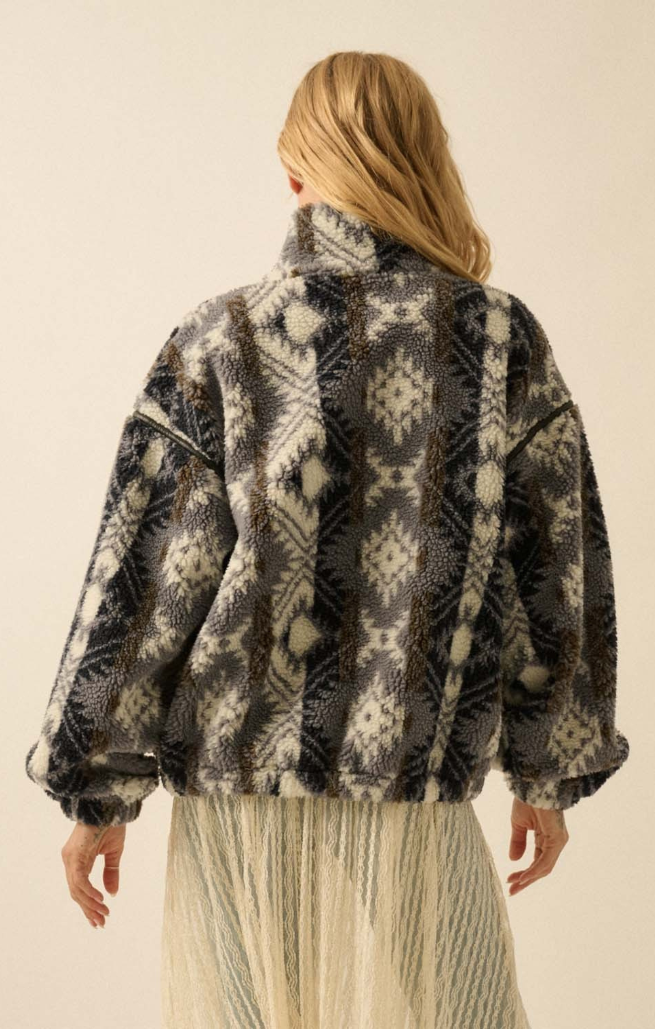 Person wearing a patterned jacket on a plain background