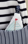 Small sailboat plush toy with a red flag inside a striped bag.