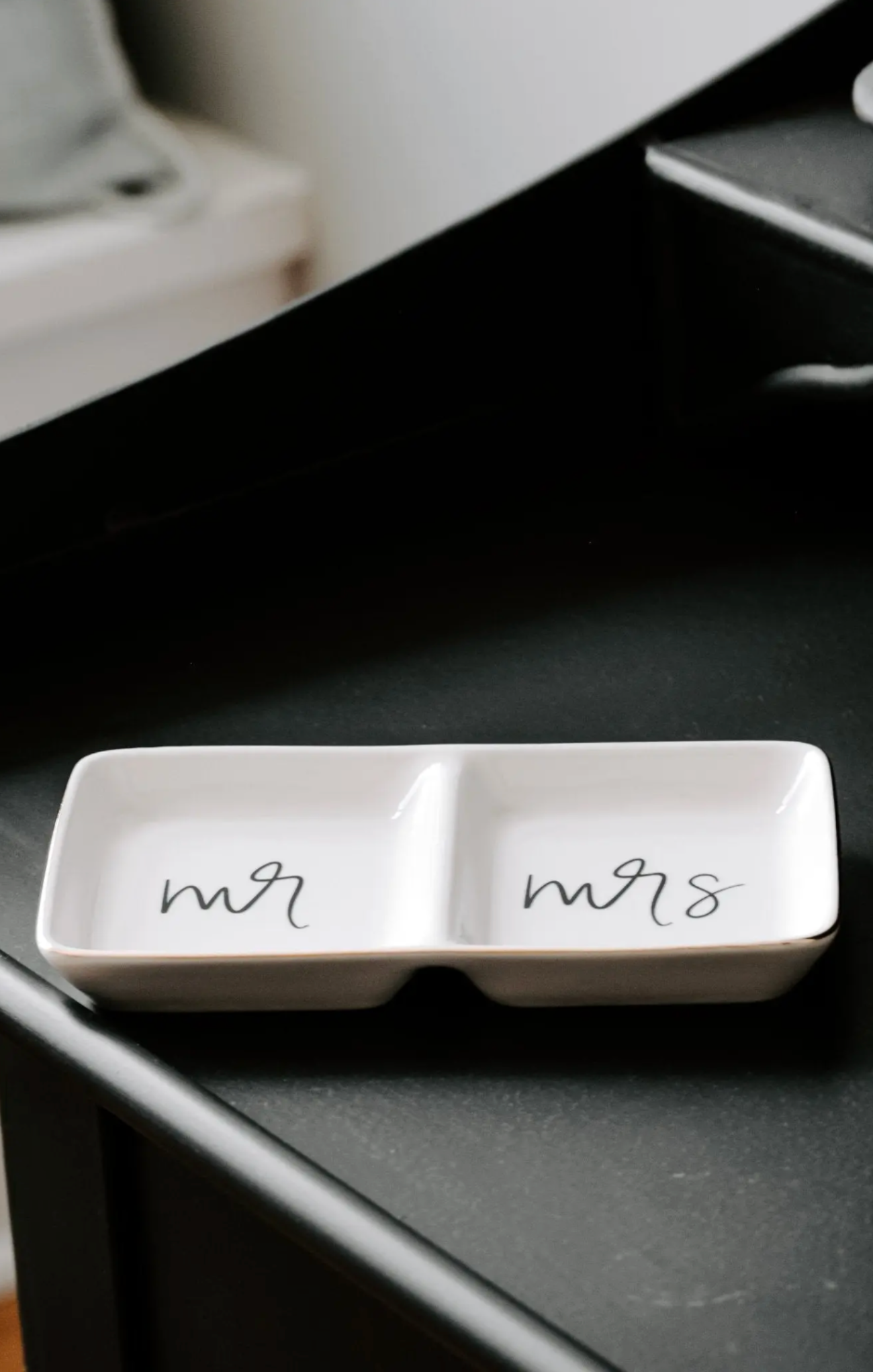 white glass dish on black counter with mr and mrs on dish