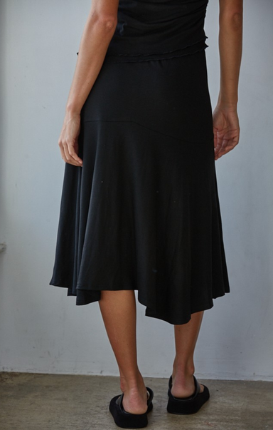 Person wearing a black skirt against a plain background