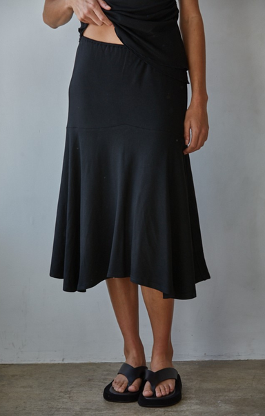 Person wearing a black skirt against a plain background