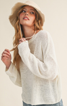 Woman wearing a white knit sweater and beige hat against a plain background