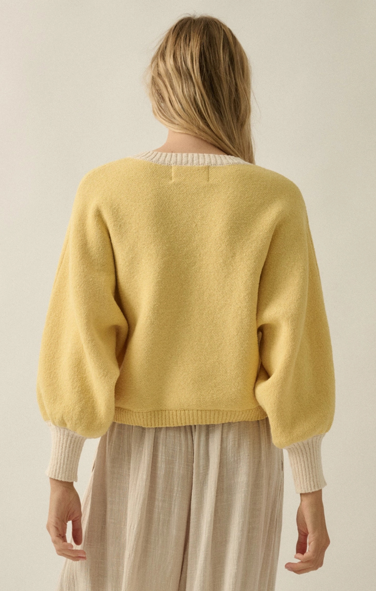Person wearing a yellow sweater with a neutral background