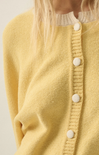 Yellow cardigan with white buttons on a neutral background
