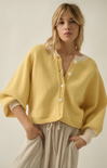 Woman wearing a yellow cardigan with a plain background