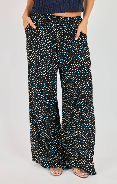 Black polka dot pants worn by a person on a light gray background