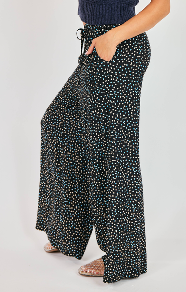 Black floral-patterned wide-leg pants worn by a person on a white background