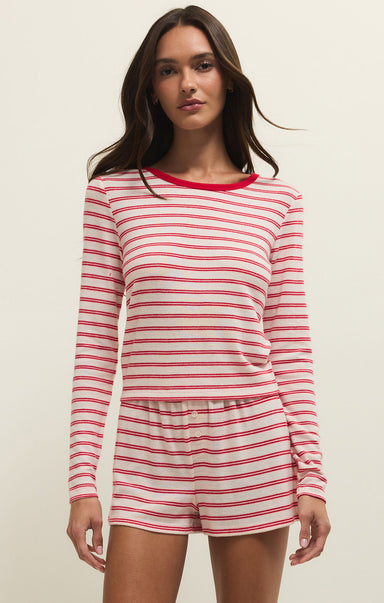 Woman wearing a red and white striped pajama set on a beige background