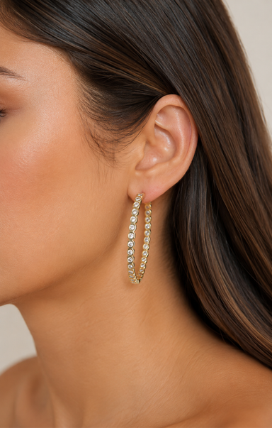 Gold hoop earrings with clear gemstones on a white background