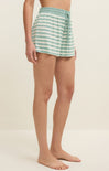 Person wearing green and white striped shorts on a beige background