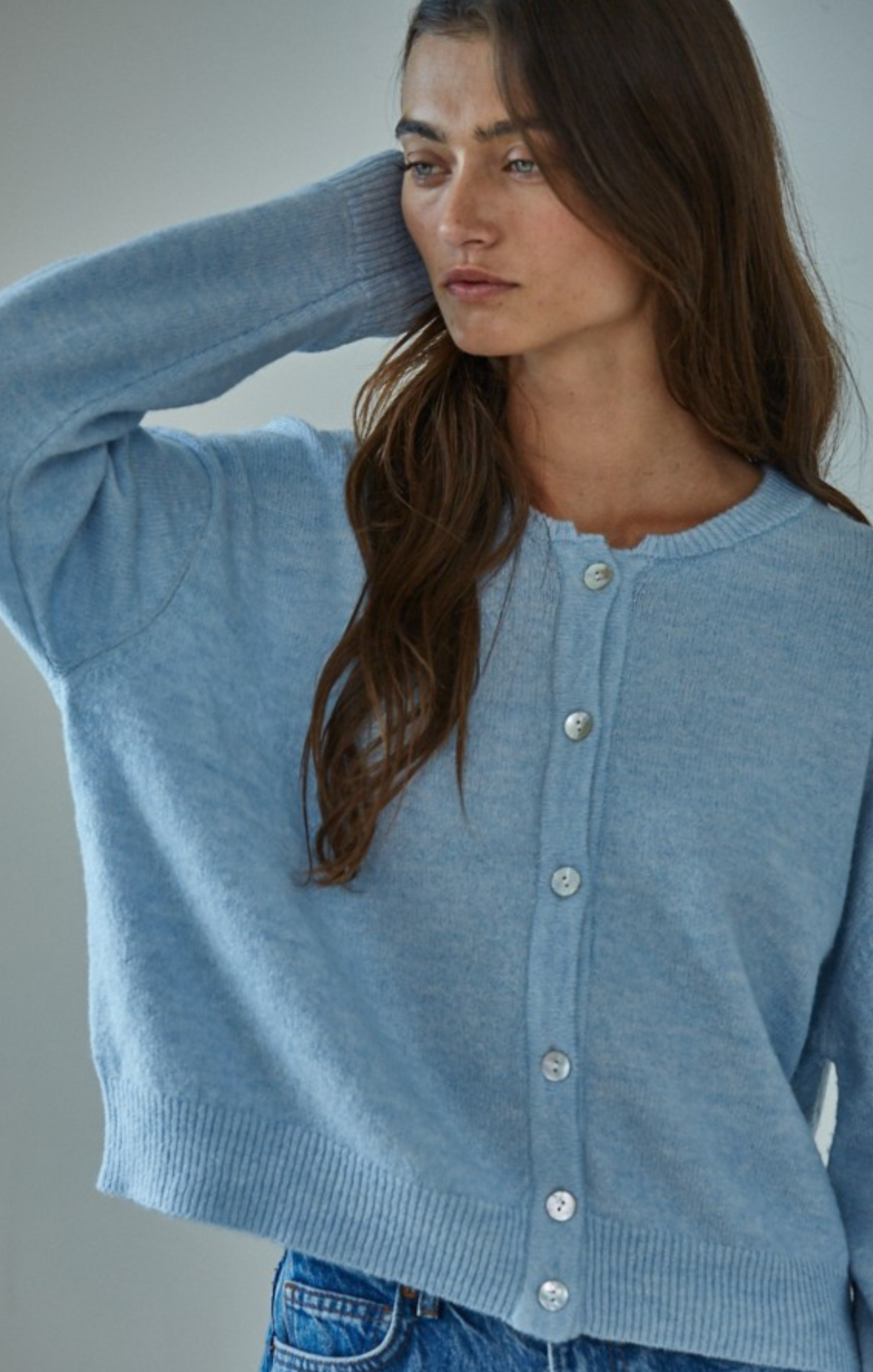 Woman wearing a light blue cardigan against a neutral background