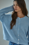 Woman wearing a light blue cardigan against a neutral background