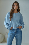 Woman wearing a light blue cardigan and jeans against a plain background
