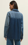 Person wearing a blue denim jacket on a plain background