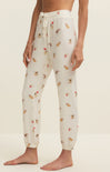 White pajama pants with small patterns worn by a person on a beige background