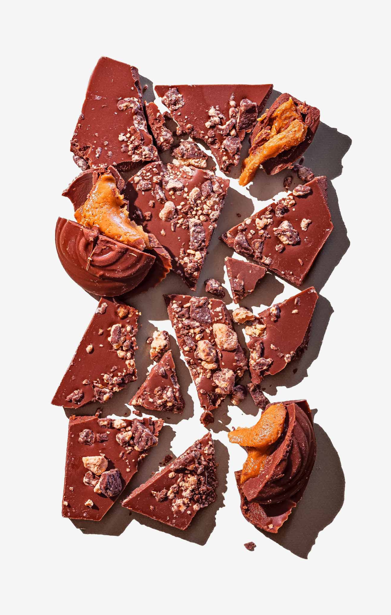 Broken pieces of chocolate with nuts on a white background