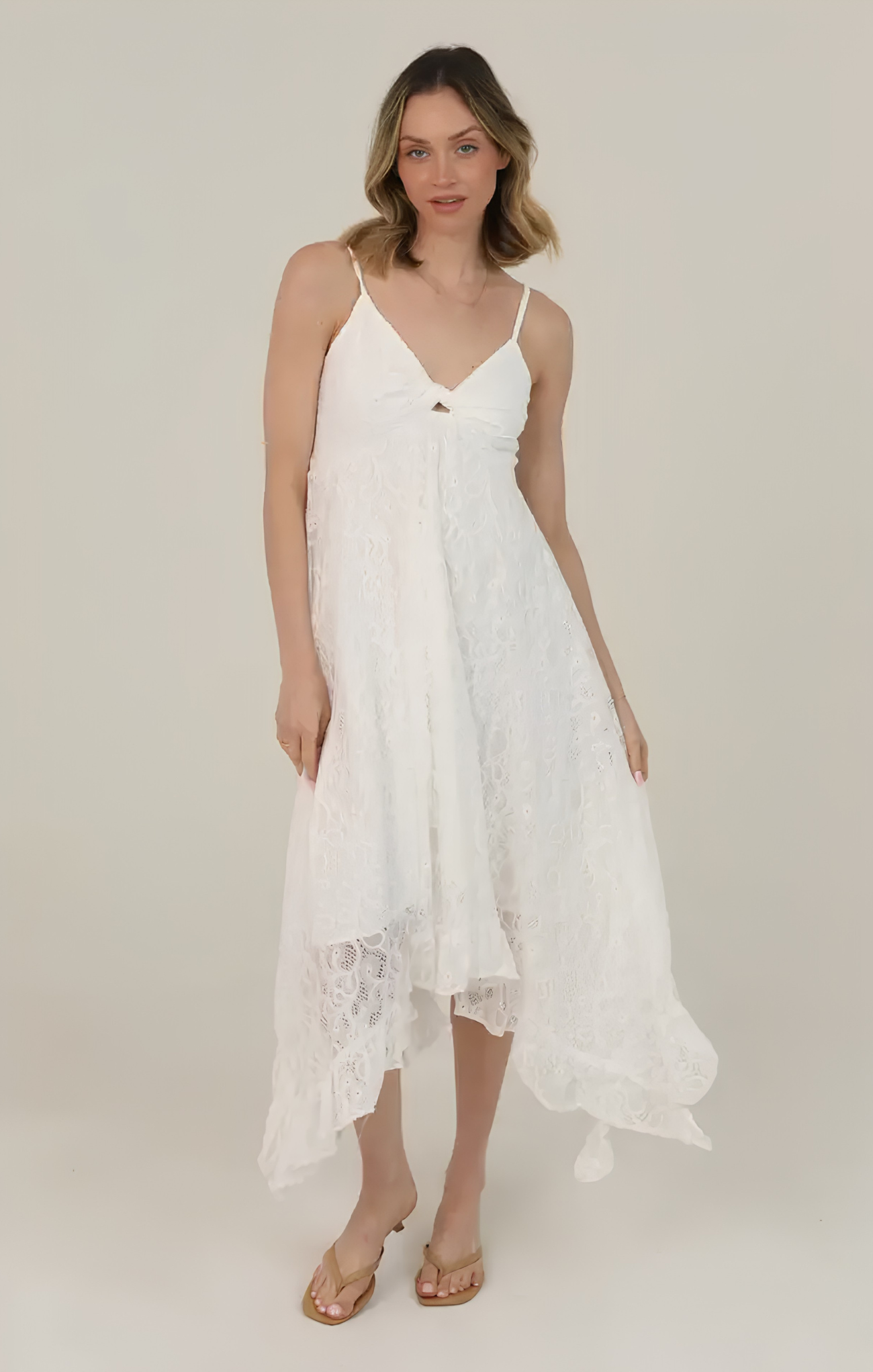 Woman wearing a white lace dress on a plain background