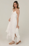 Woman wearing a white dress with thin straps on a plain background