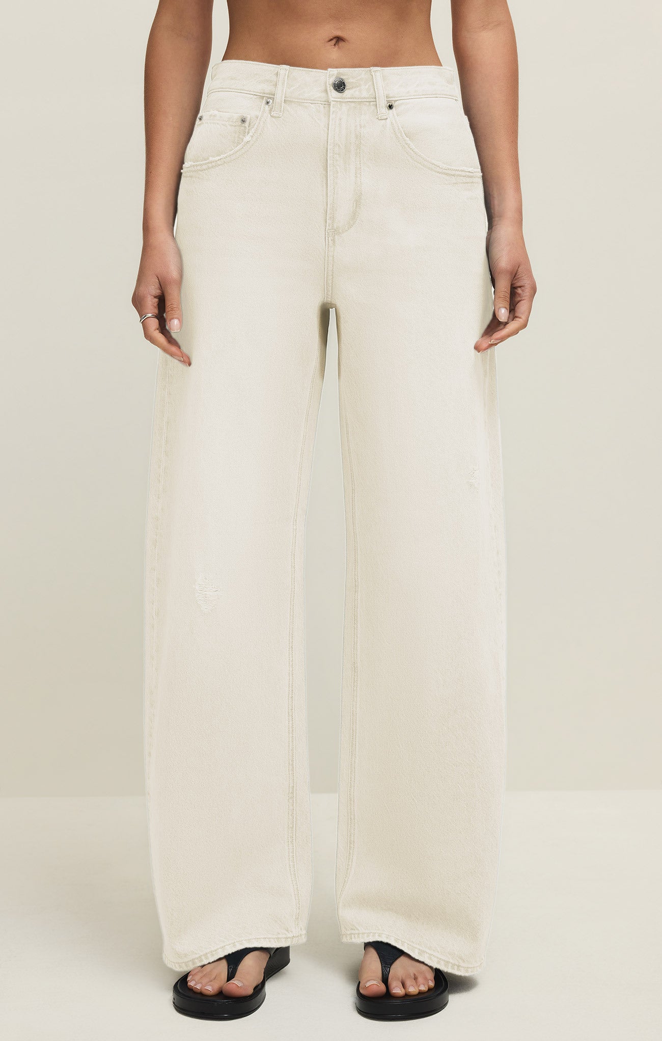 Person wearing white wide-leg jeans on a plain background