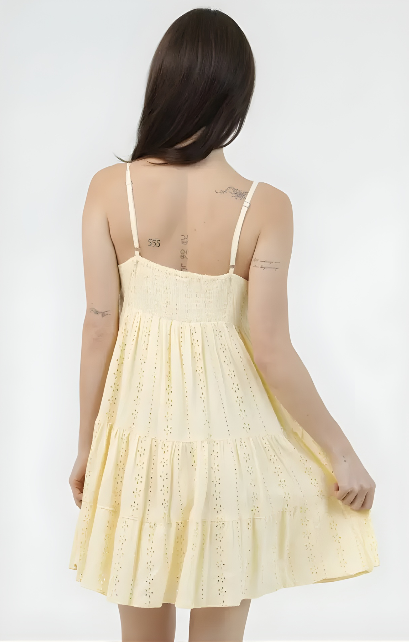 Woman wearing a yellow lace dress against a white background