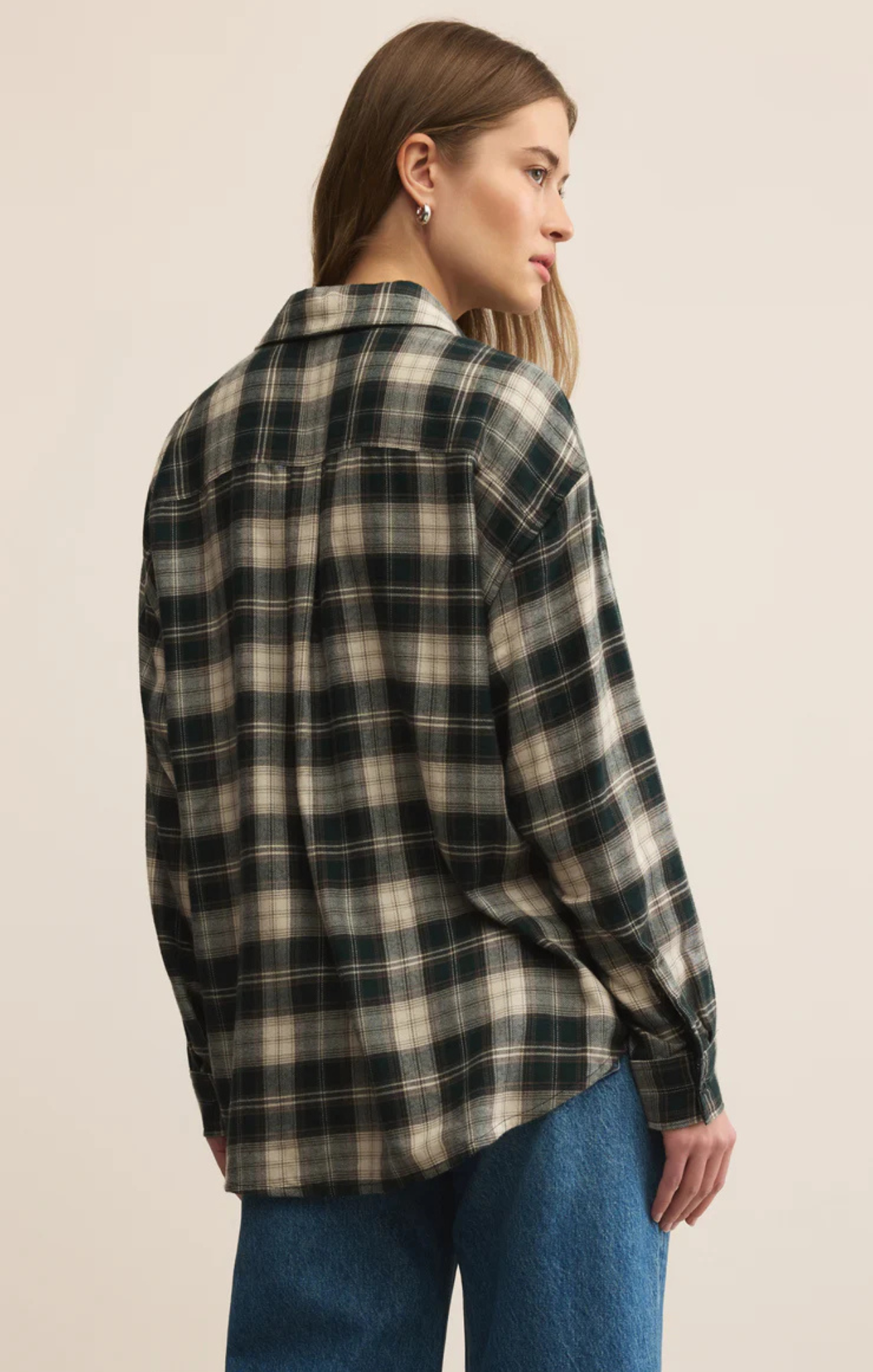 Person wearing a plaid shirt and jeans on a beige background