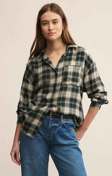 Woman wearing a plaid shirt and jeans against a beige background