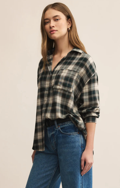 Woman wearing a plaid shirt and jeans against a beige background