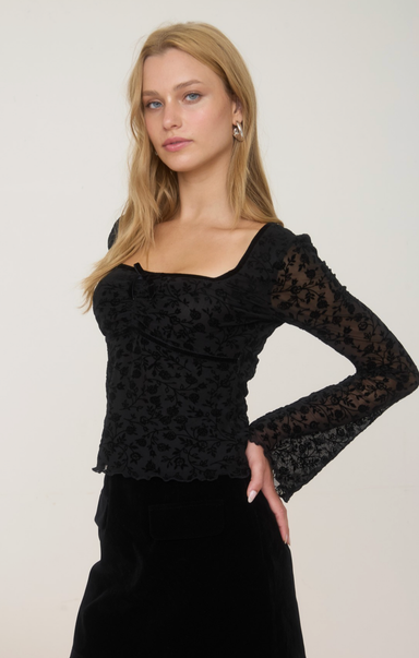 Woman wearing a black lace top against a white background