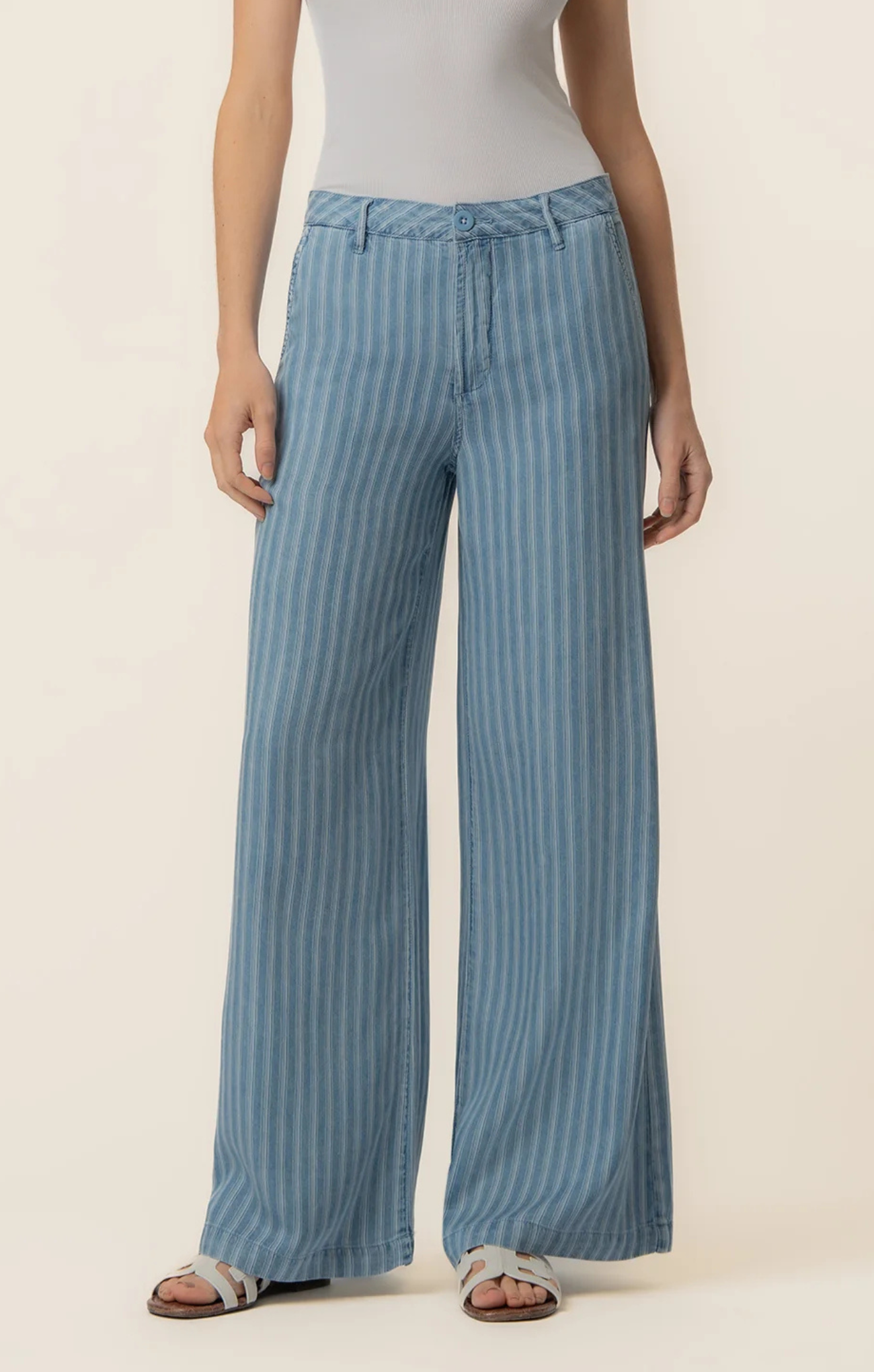 Person wearing blue striped pants on a beige background