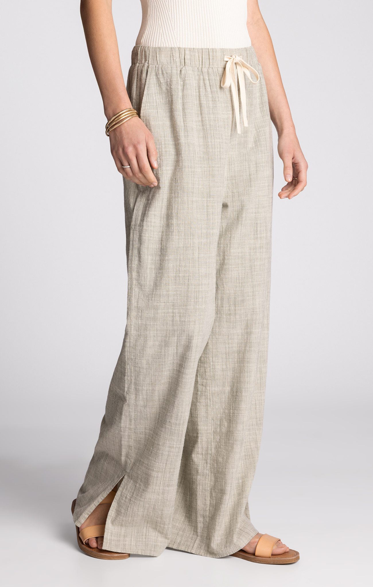 Person wearing light-colored wide-leg pants on a plain background