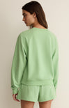 Woman wearing a light green sweatshirt and shorts set on a beige background