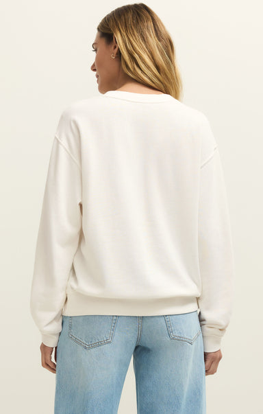 Person wearing a white sweatshirt and light blue jeans on a plain background
